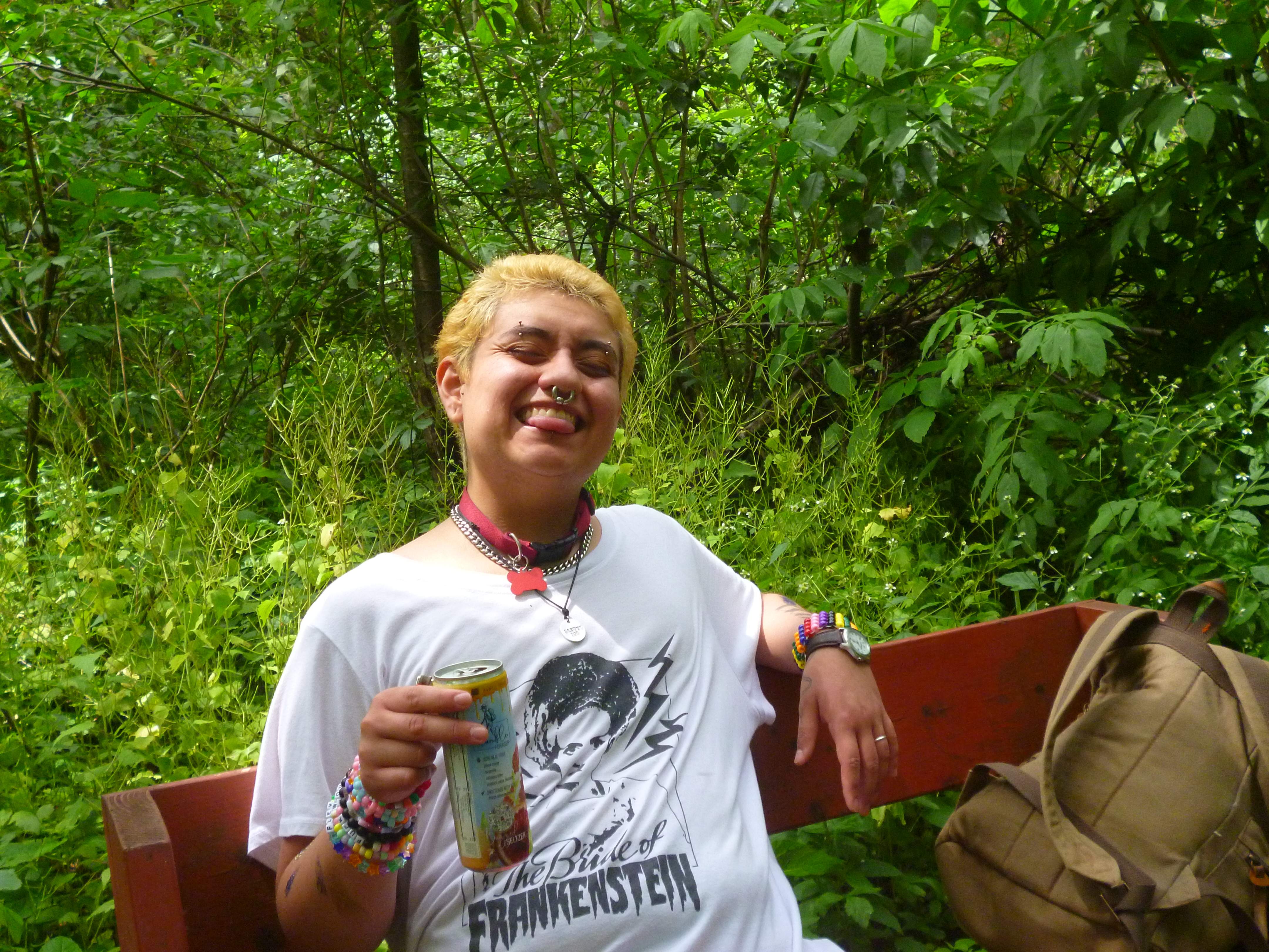 David on a bench in the woods at pride.